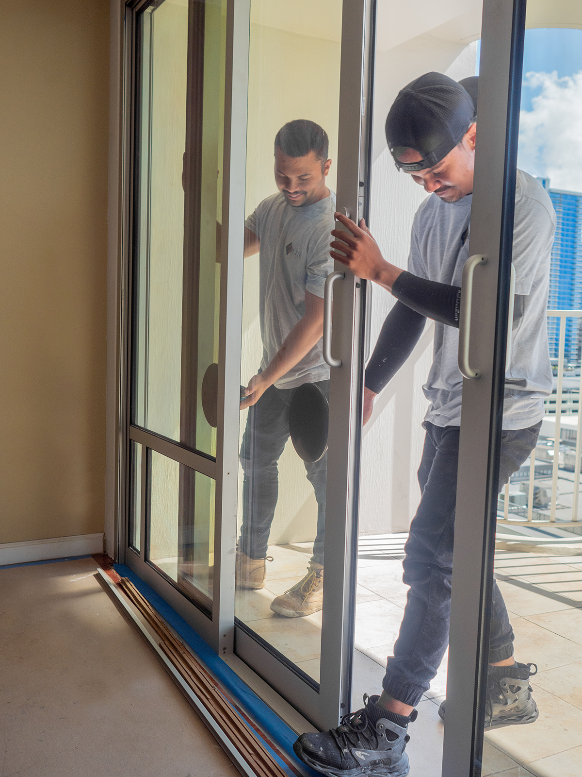 Two men are working on a sliding glass door