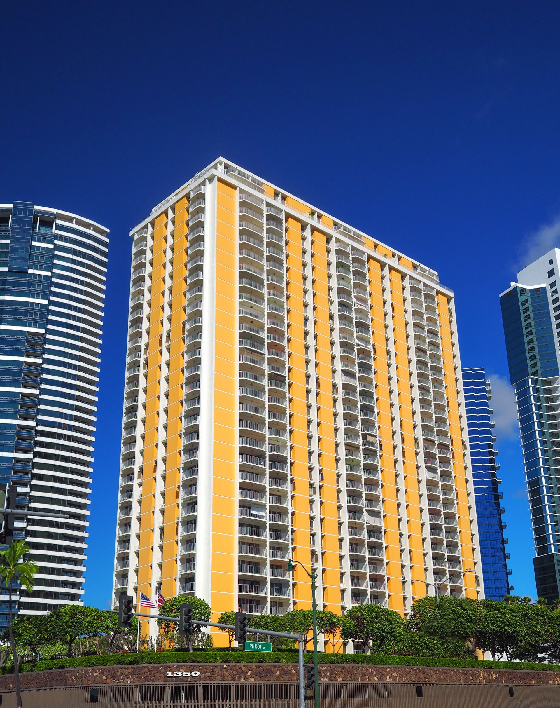 A tall yellow building with a blue sky in the background