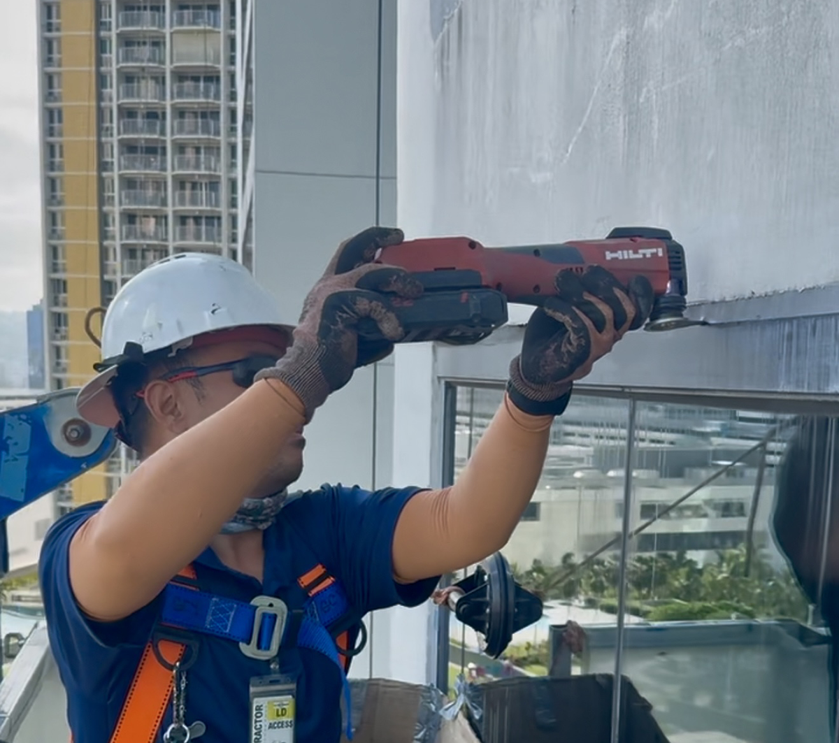 A man wearing a hard hat is using a tool that says hilti