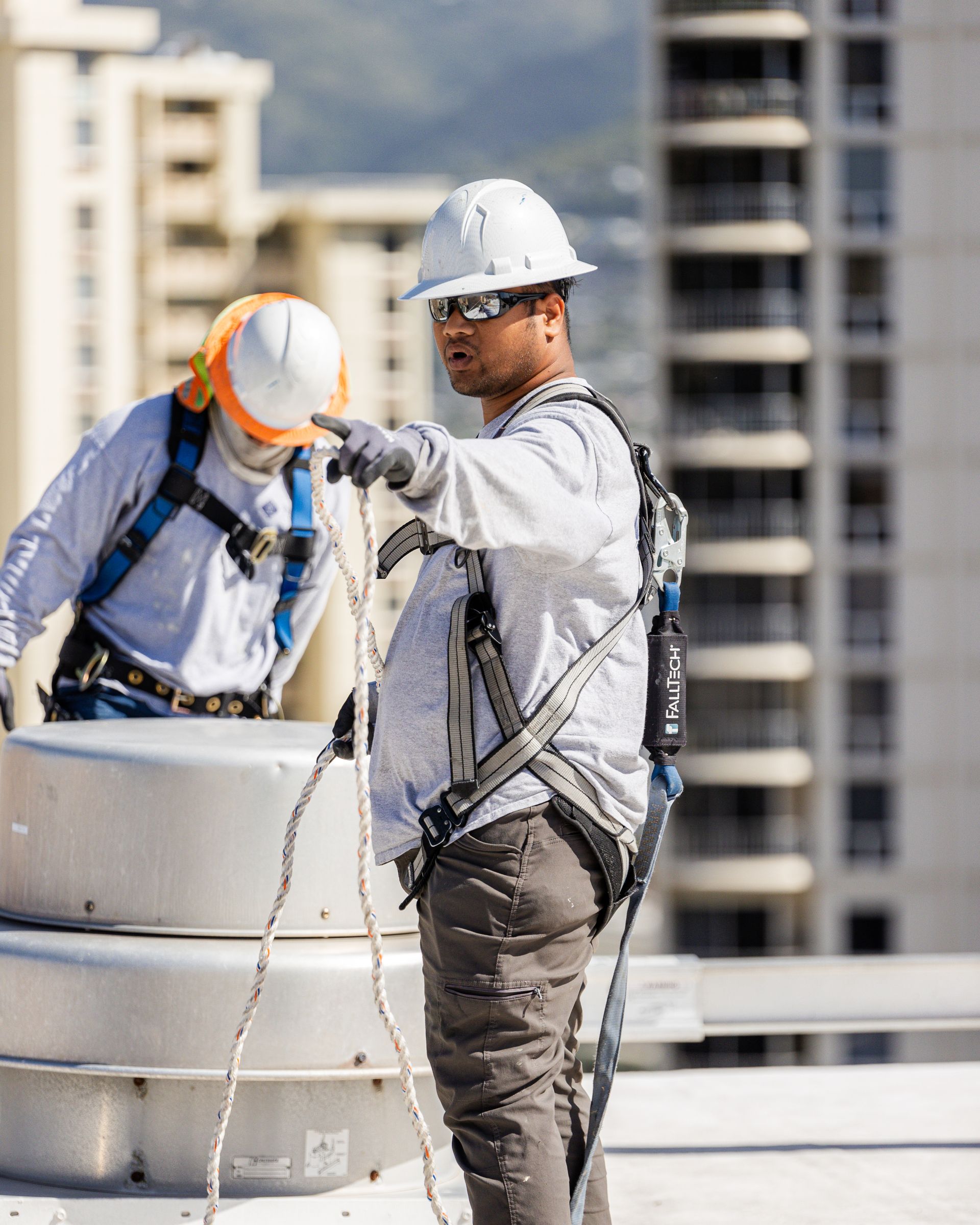 A man wearing a hard hat is working on a balcony.