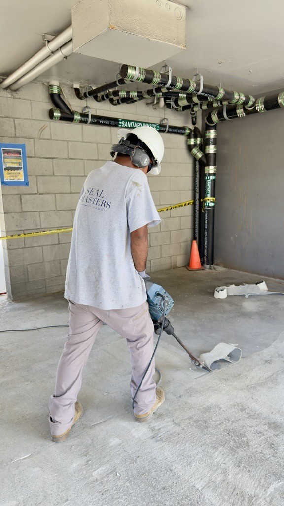 A man is using a hammer on a concrete floor.