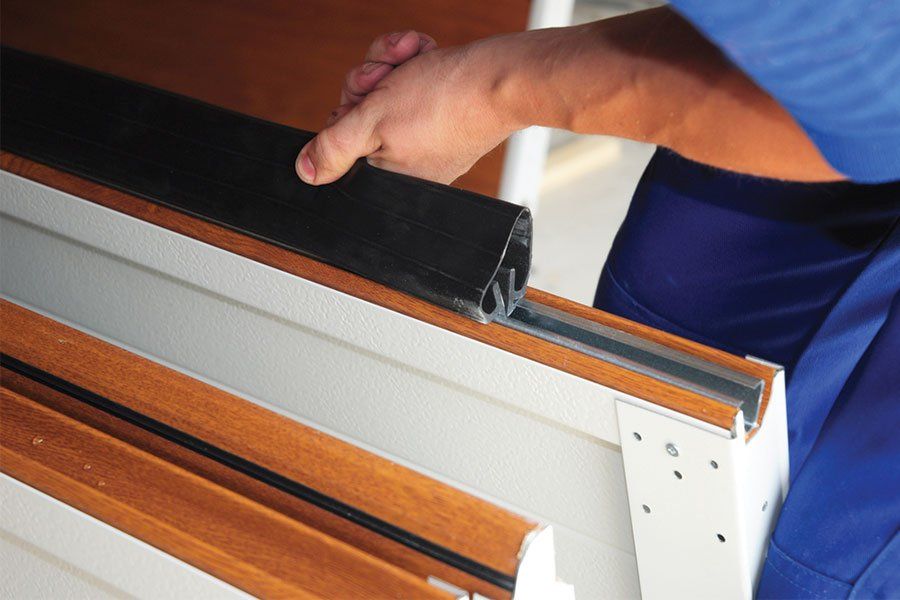 A garage door technician adding a new garage door seal in Aurora, IL.