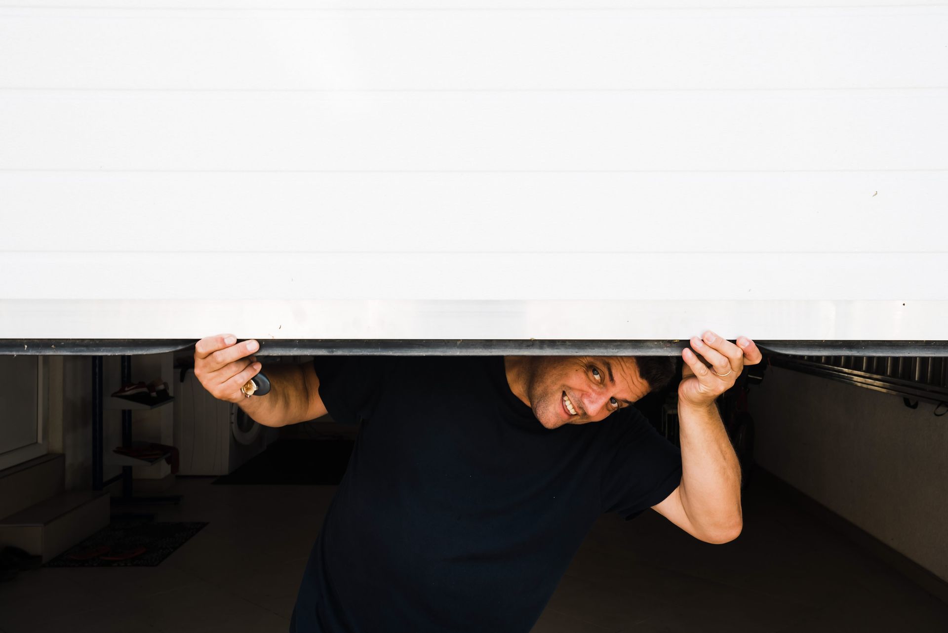A man underneath a half-open garage door.