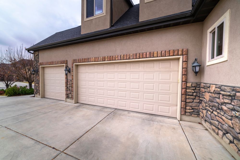 A large house with three garage doors and a stone wall.