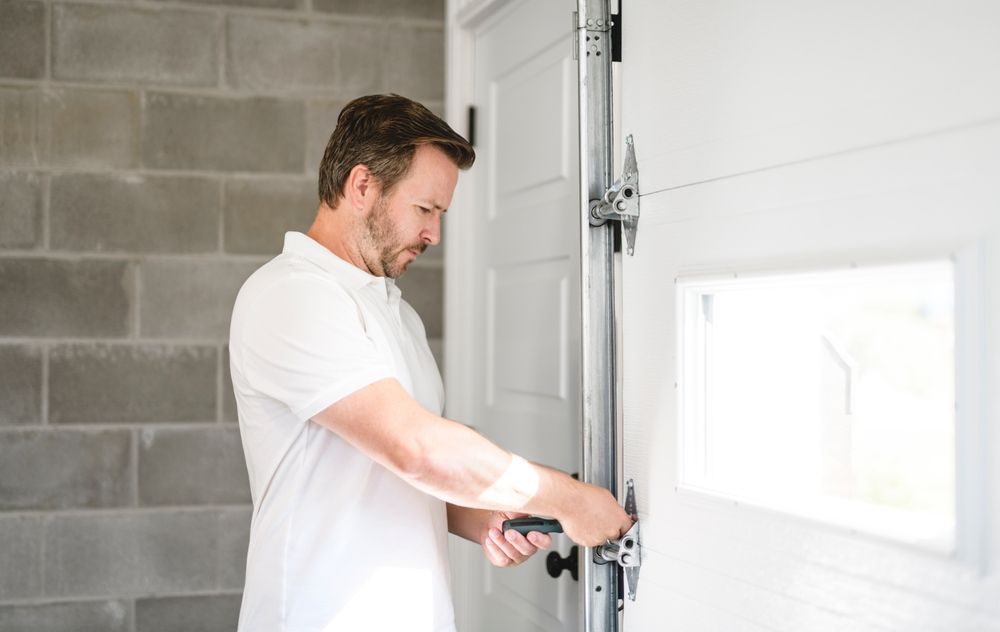 A man is opening a garage door with a screwdriver.