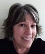 Woman with short gray and brown hair smiles at the camera.