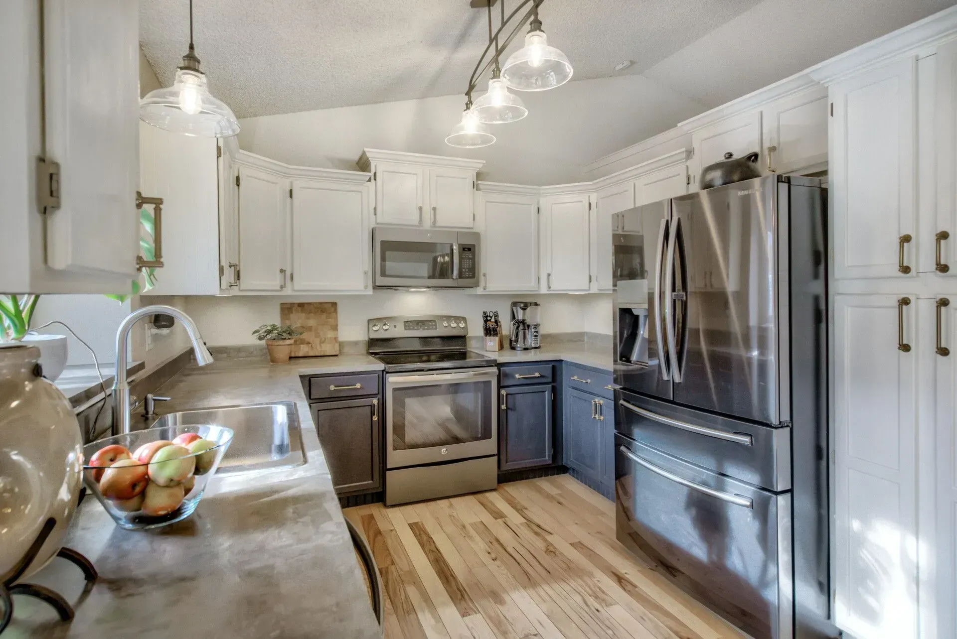 Modern white kitchen with stainless steel appliances, gray cabinets, and hardwood floors