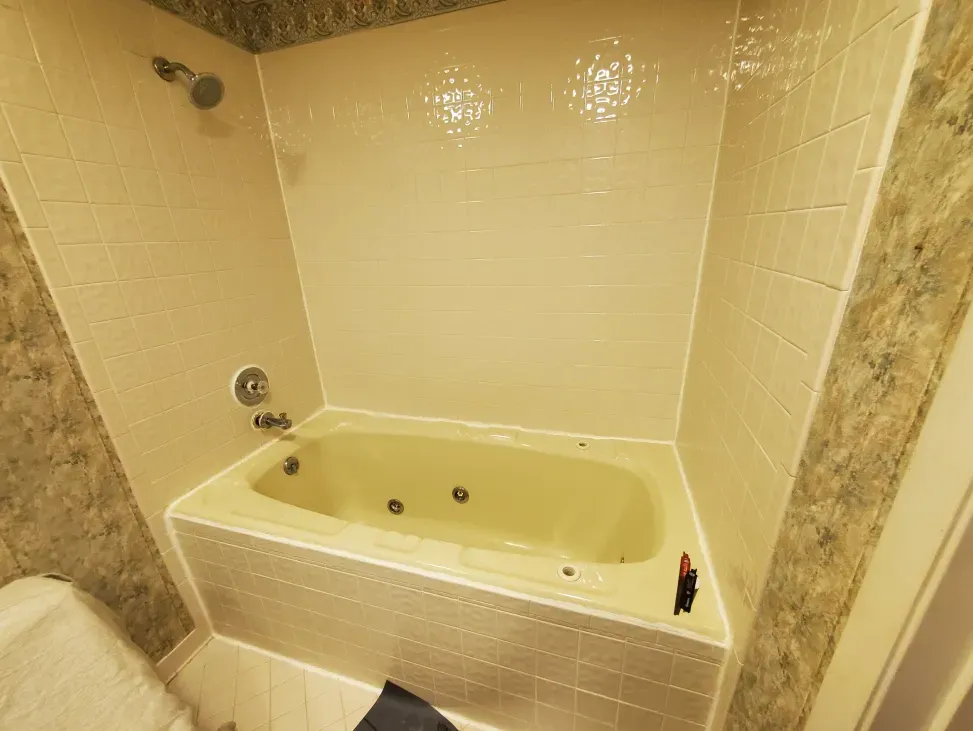 Cream-colored bathroom with a built-in bathtub, tiled surround, and stone wall accents.