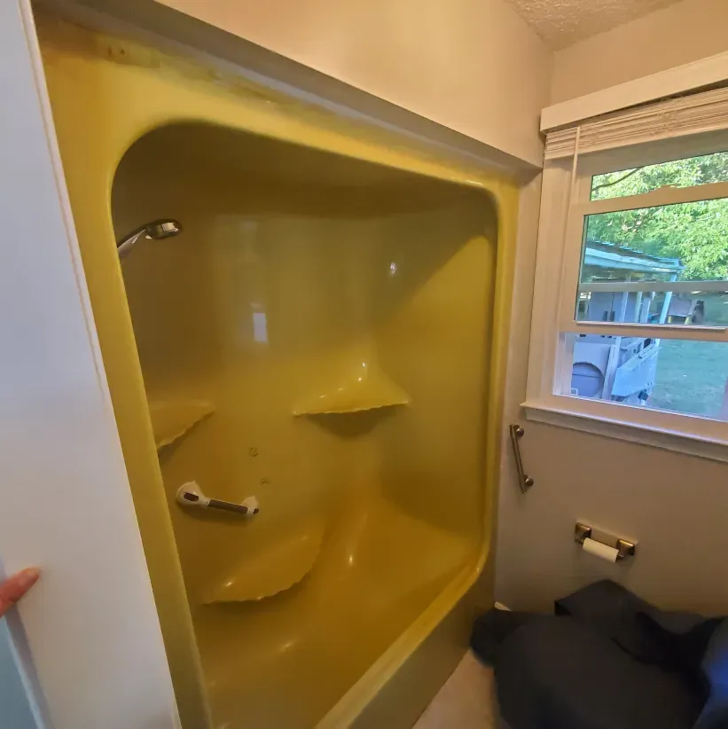 Yellow tiled walk-in shower with built-in shelves and a window beside it