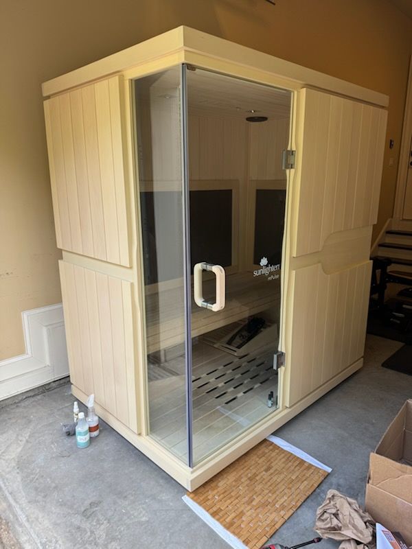 Wooden sauna room with glass door and bench seating, set indoors on a tiled floor.
