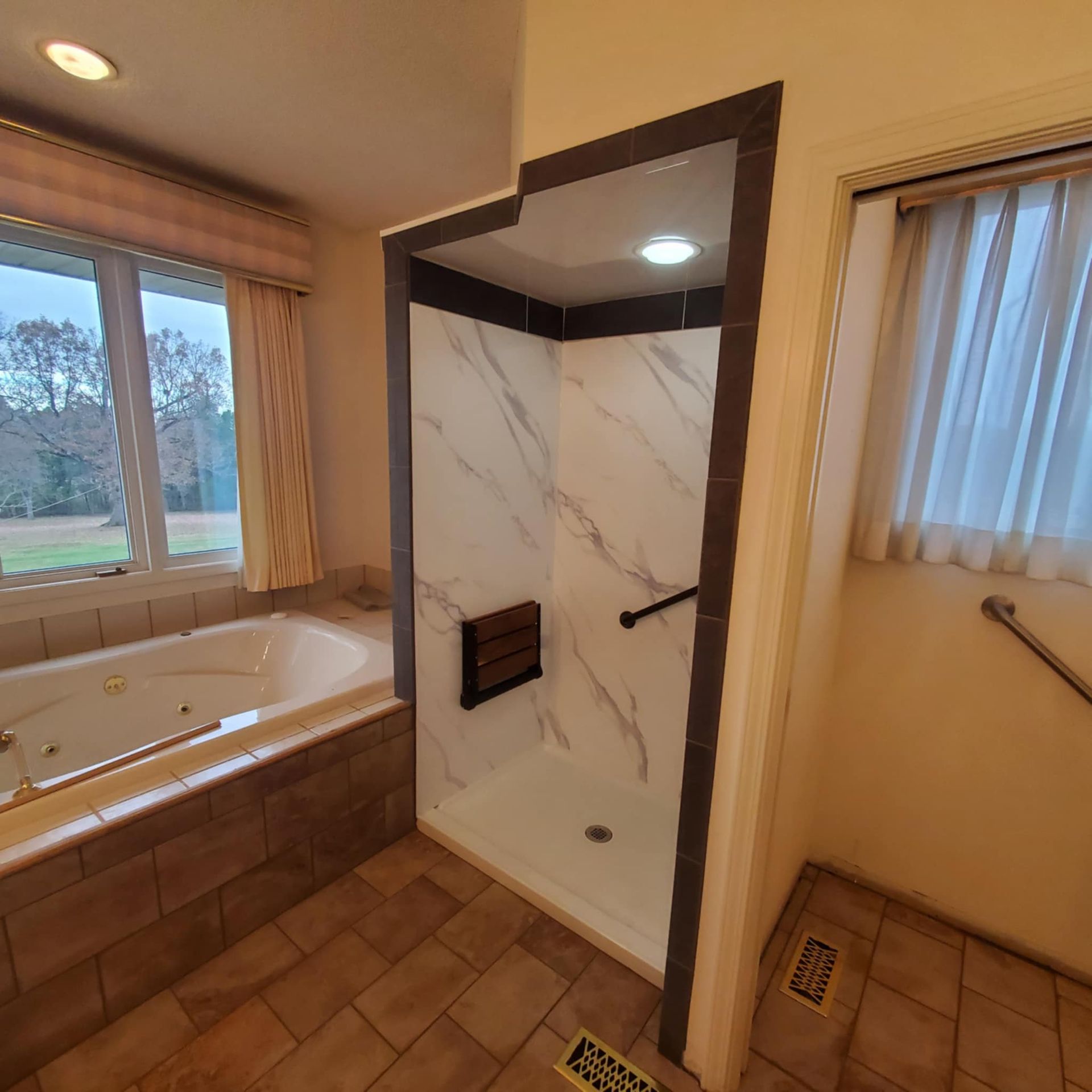 Bathroom with walk-in shower, soaking tub, and wood-look tile flooring beside a window