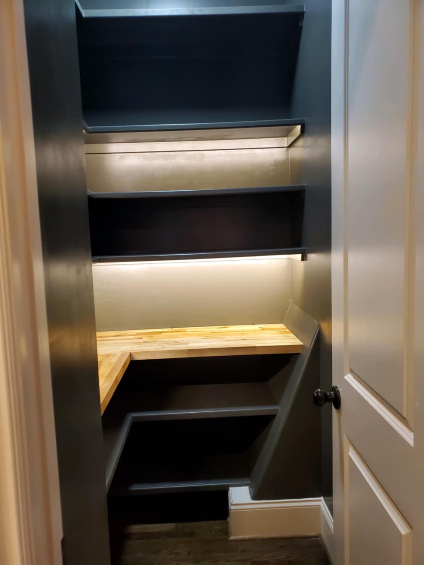 Walk-in closet with dark shelving, wood corner shelves, and built-in lighting