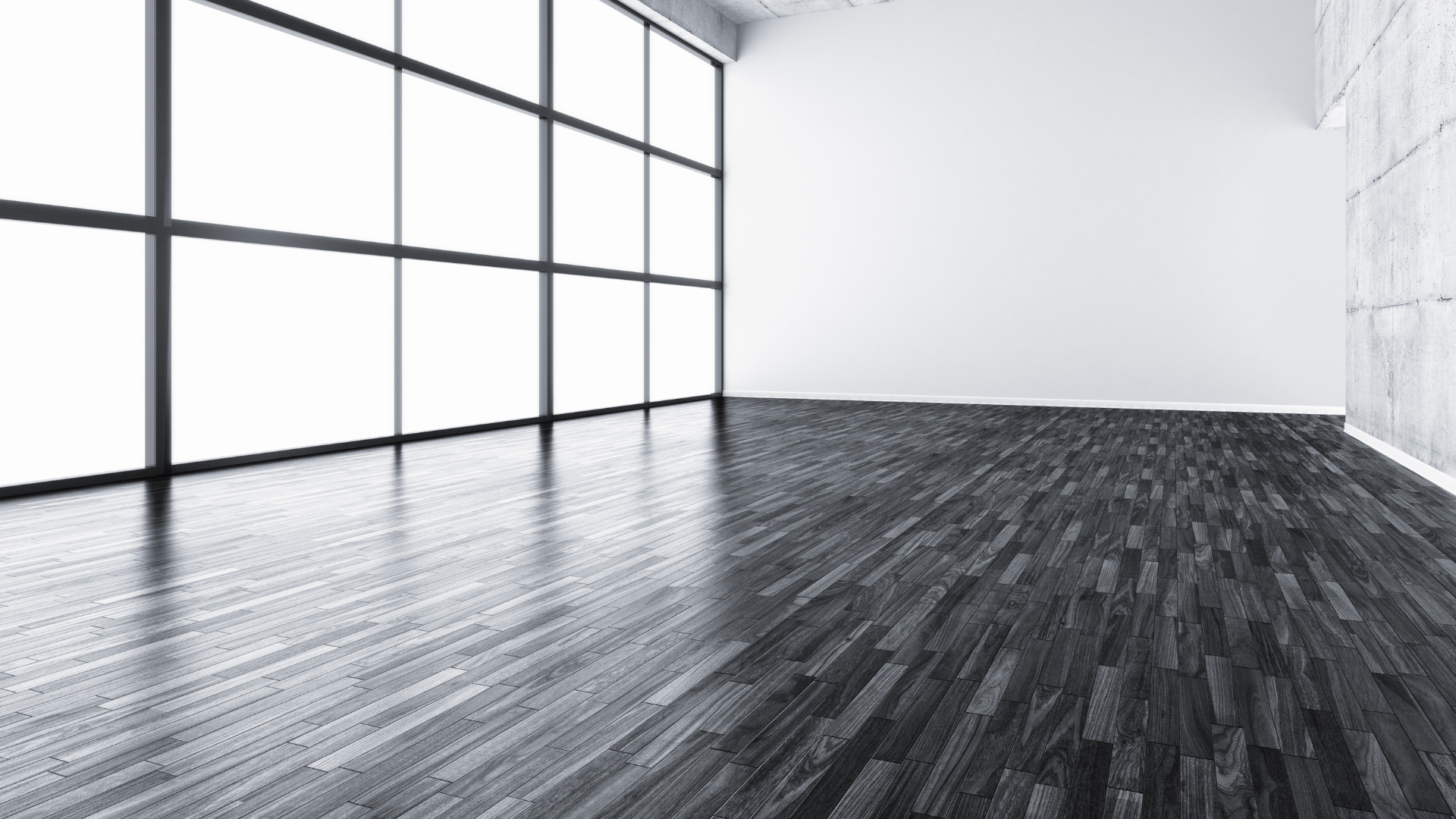An empty room with a wooden floor and large windows.
