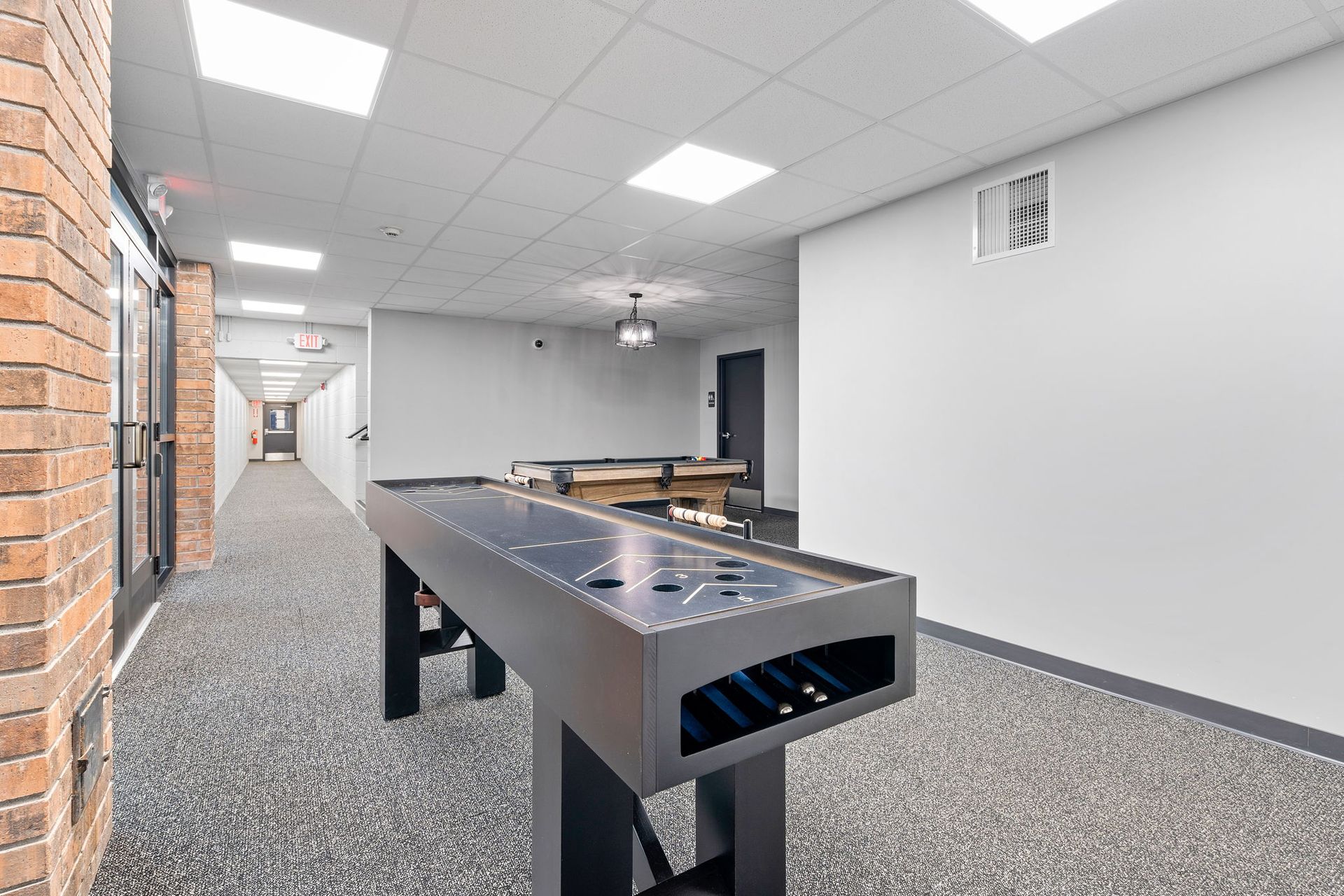 There is a shuffleboard table in the middle of a hallway.