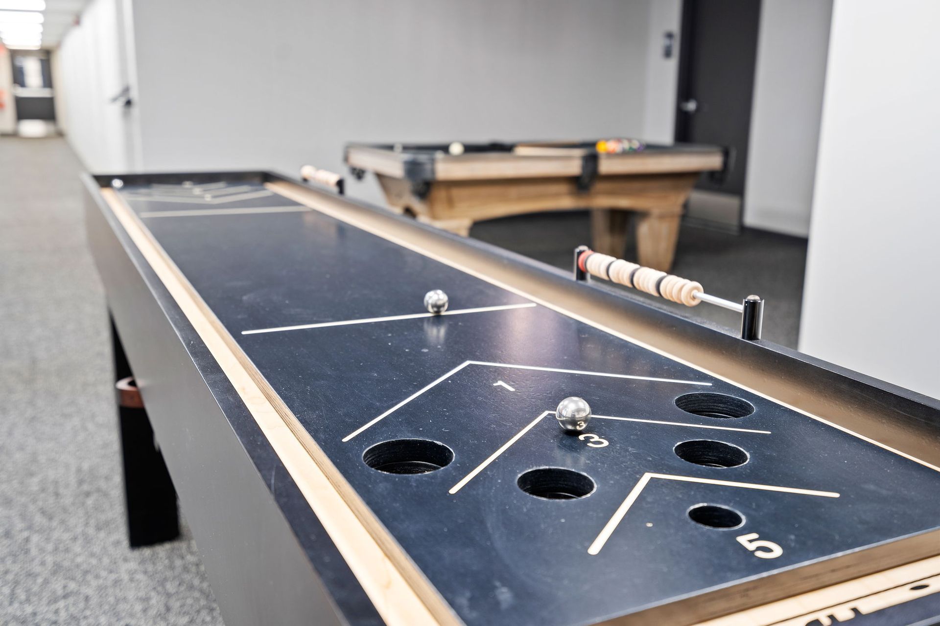 A pool table and a shuffleboard table are in a hallway.