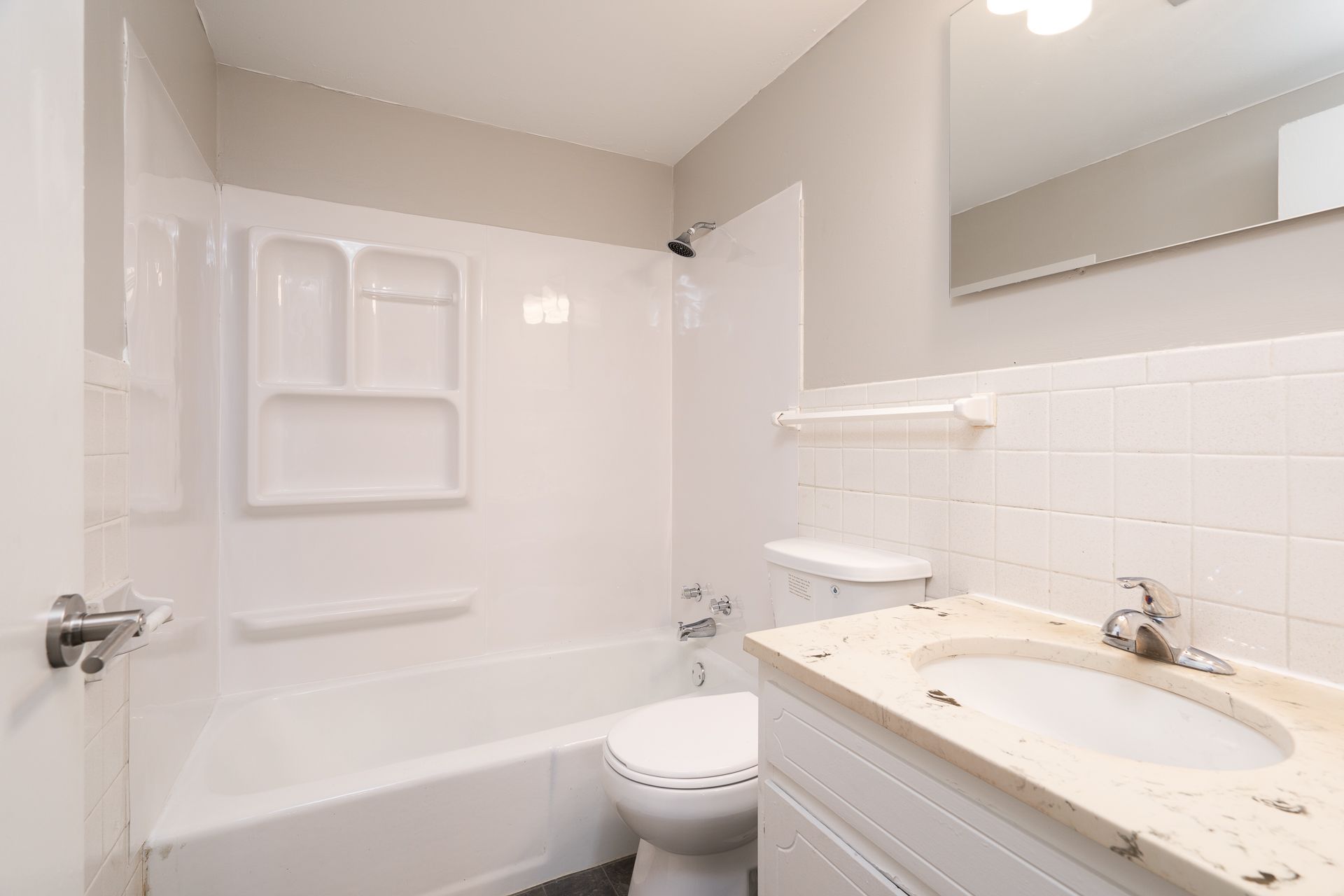 A bathroom with a toilet , sink , bathtub and mirror.