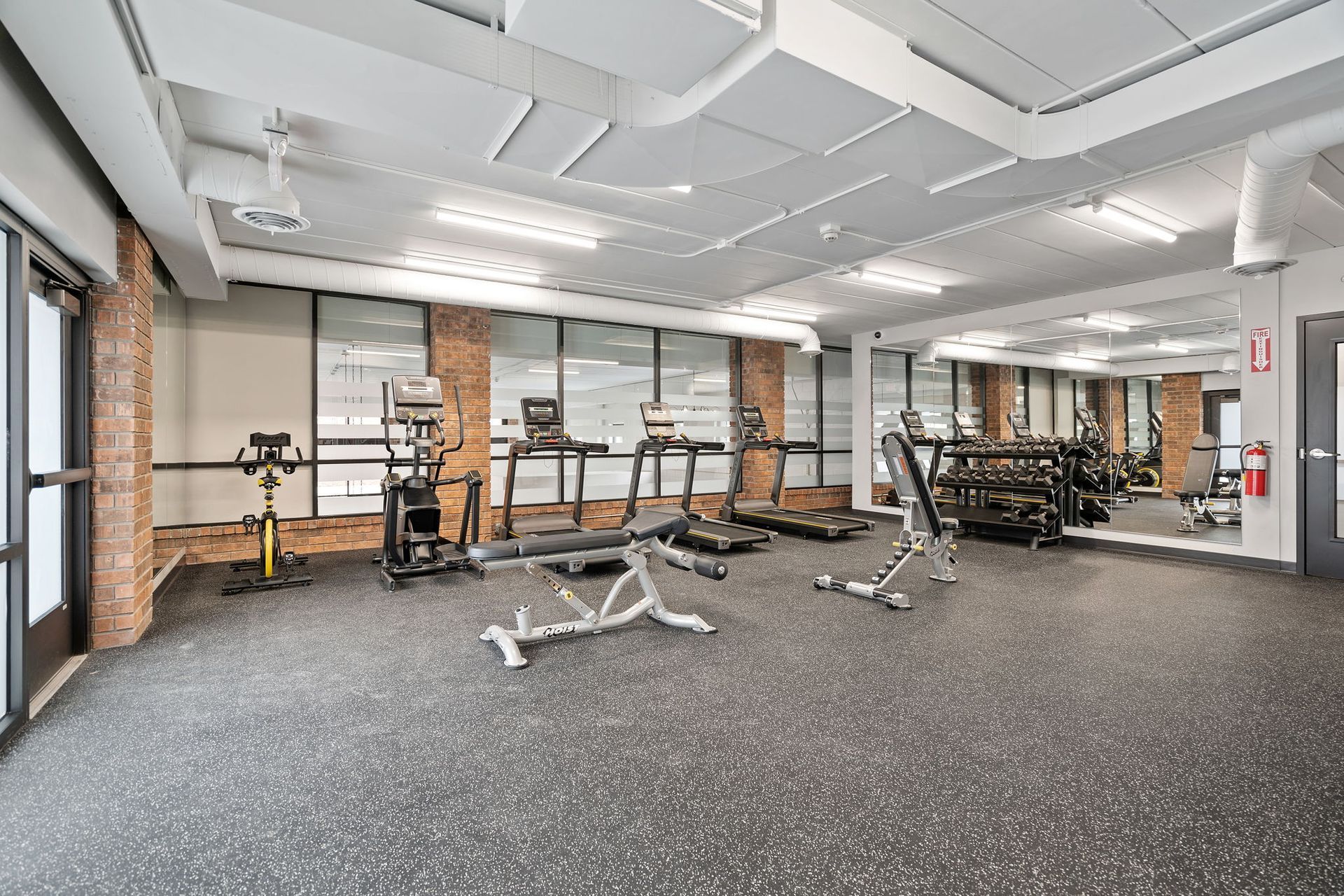 A large gym with a lot of equipment and a large mirror.