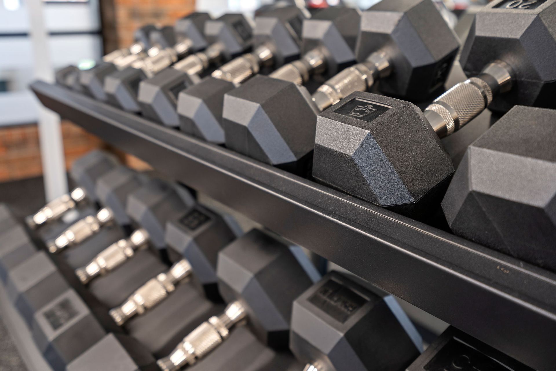 A bunch of dumbbells are stacked on top of each other on a rack.