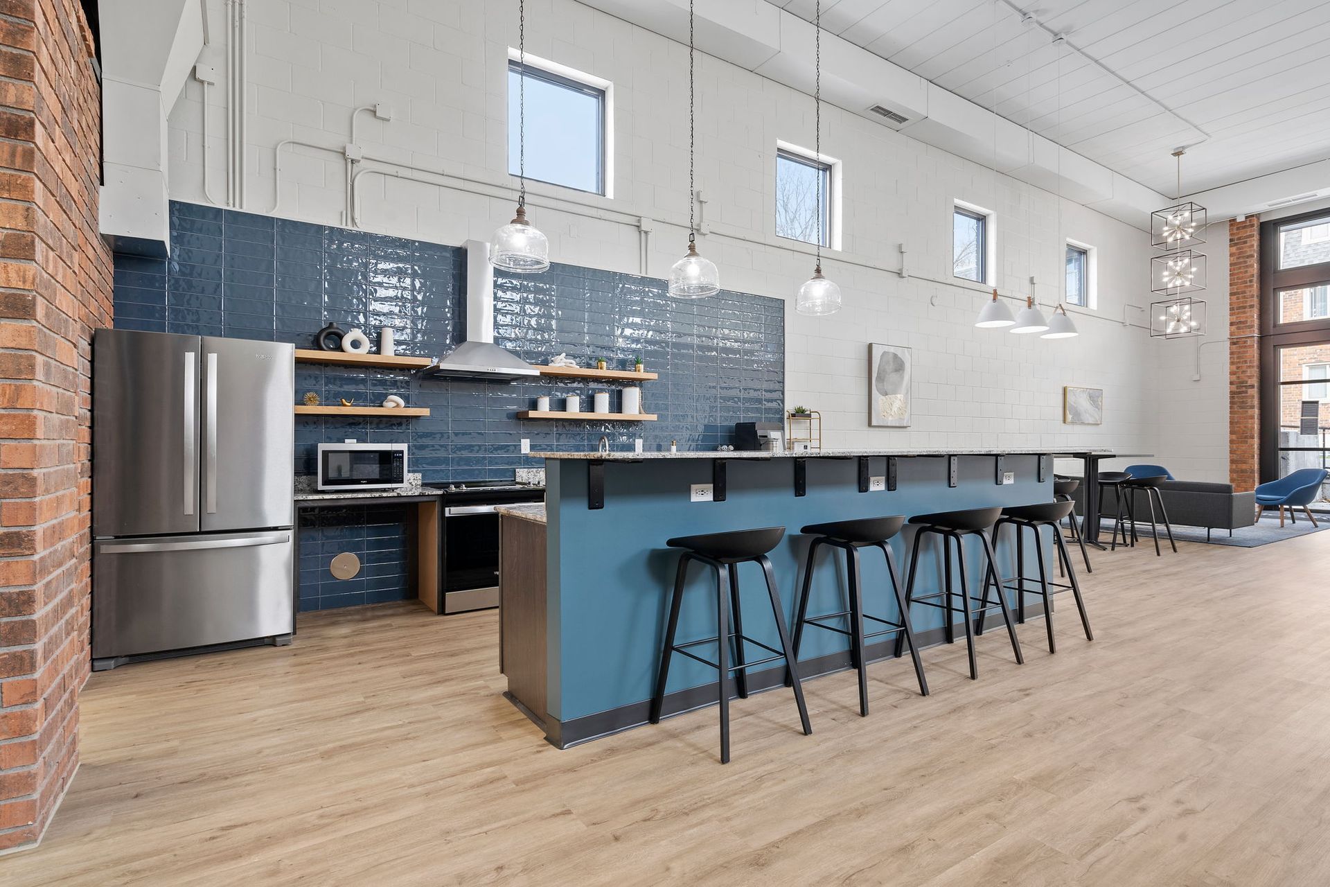 A kitchen with stools , a refrigerator , a microwave and a chalkboard on the wall.