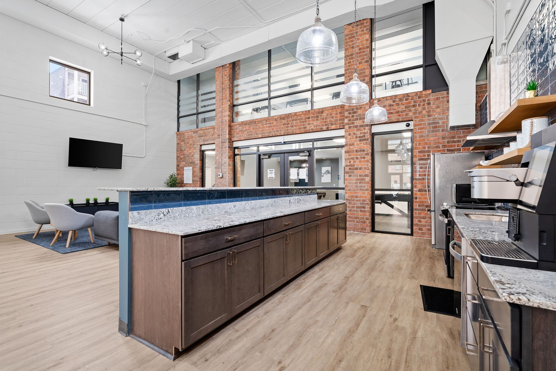 A large kitchen with stainless steel appliances and a brick wall.