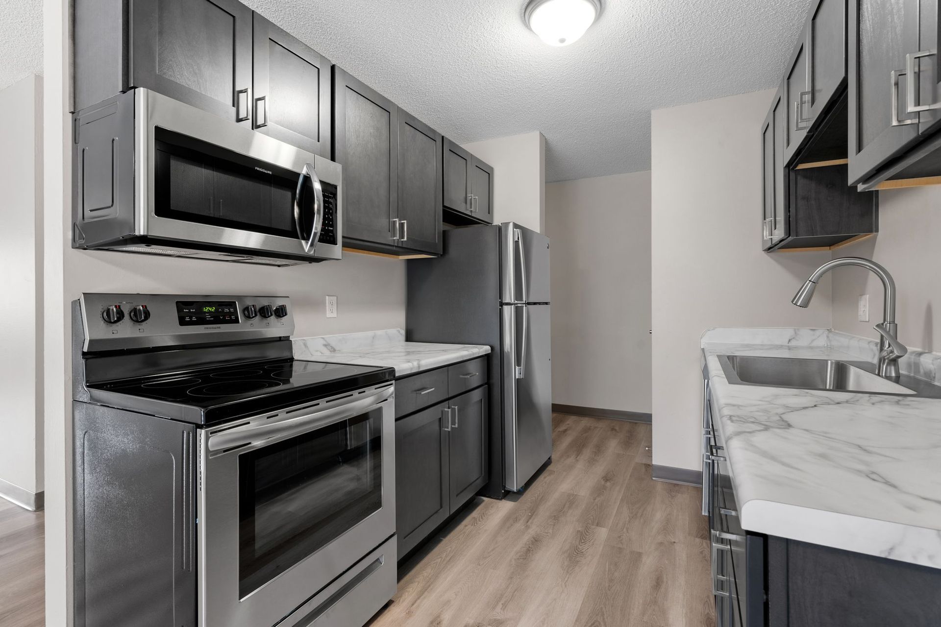 A kitchen with a stove , microwave , refrigerator and sink.
