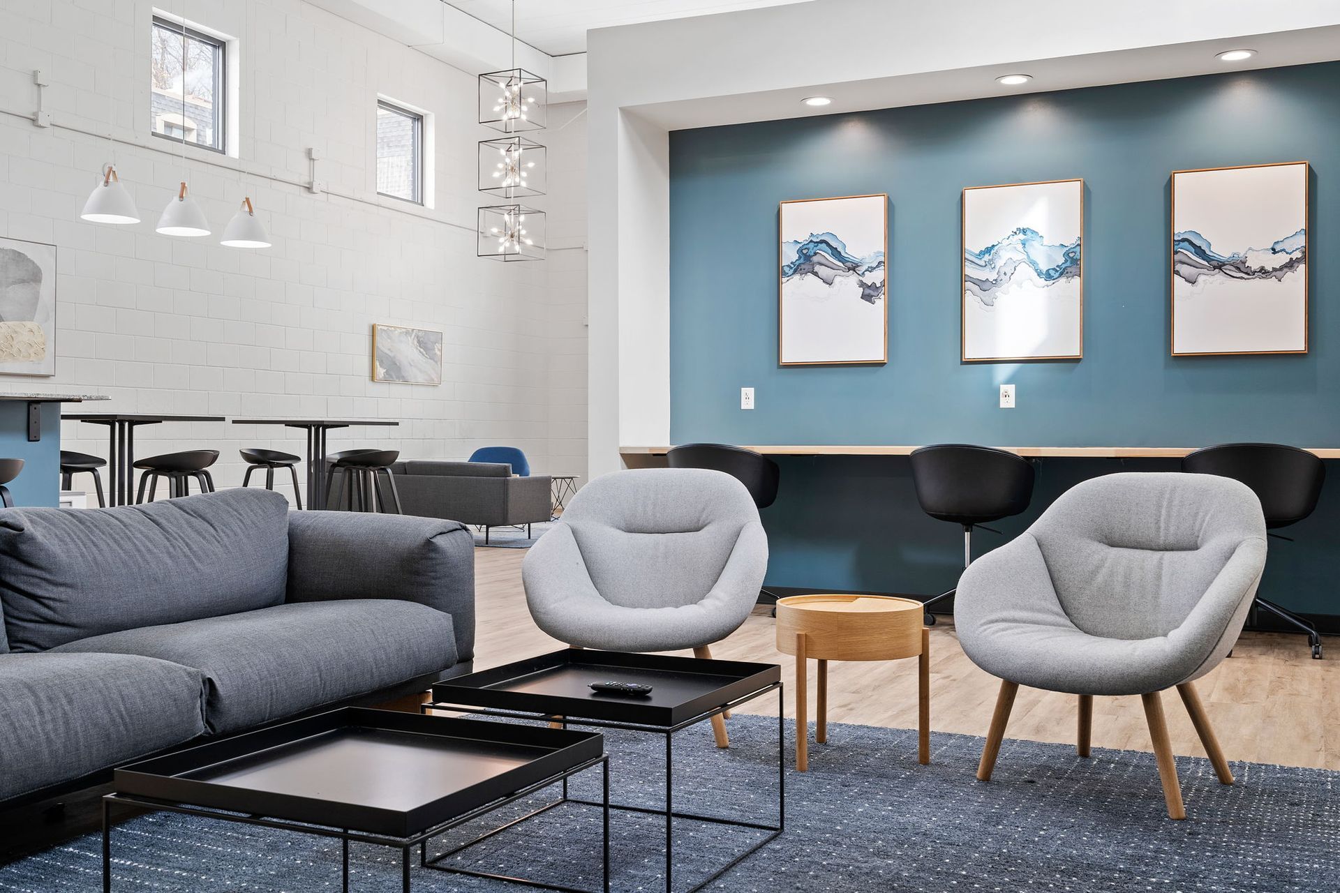 A living room with a couch , chairs , tables and a blue wall.