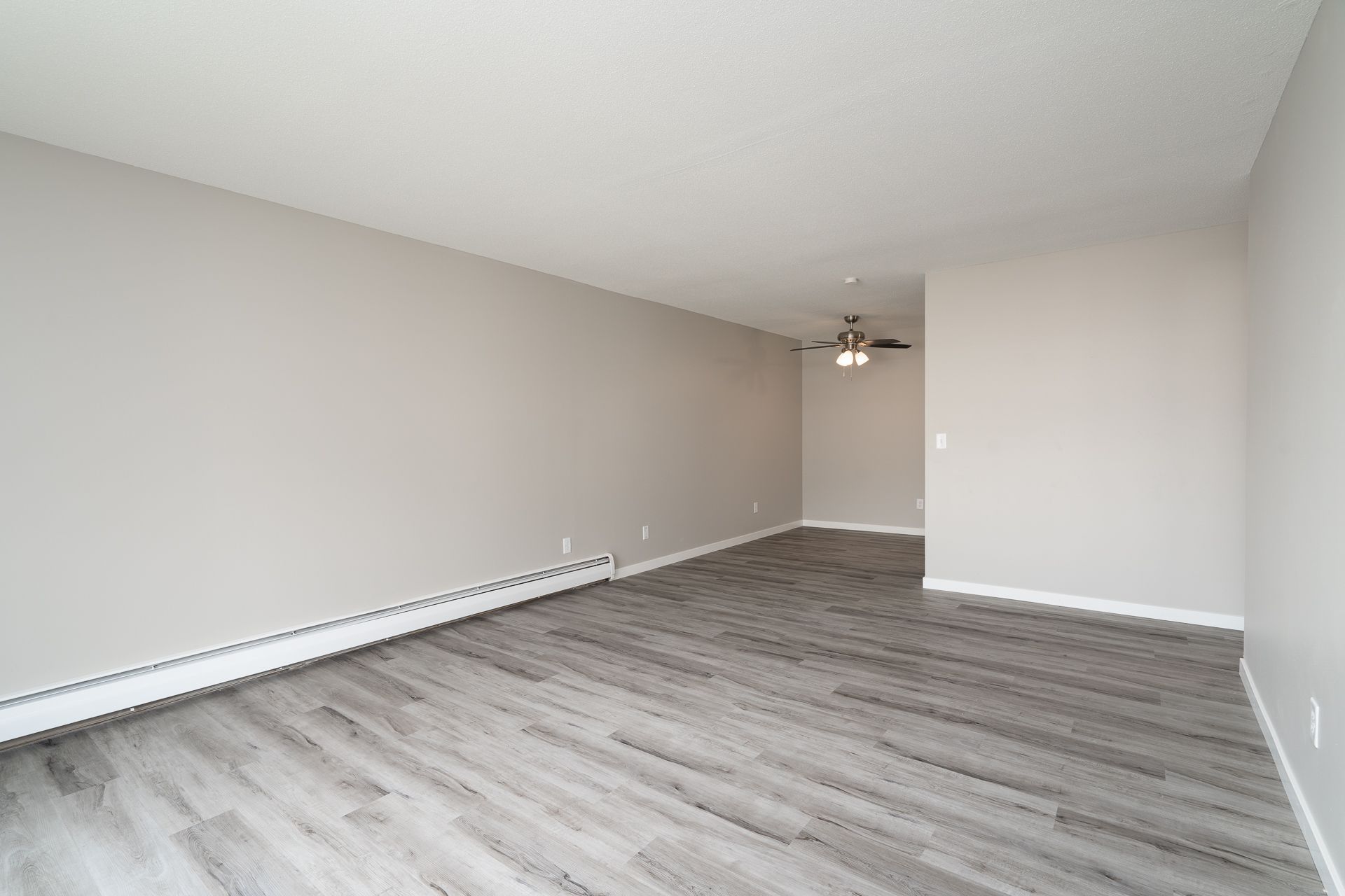 An empty living room with hardwood floors and a ceiling fan.
