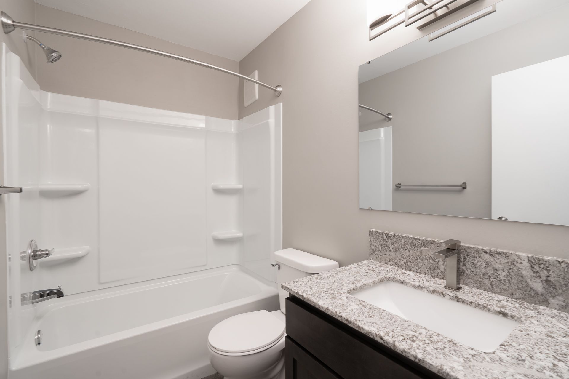 A bathroom with a toilet , sink , bathtub and mirror.