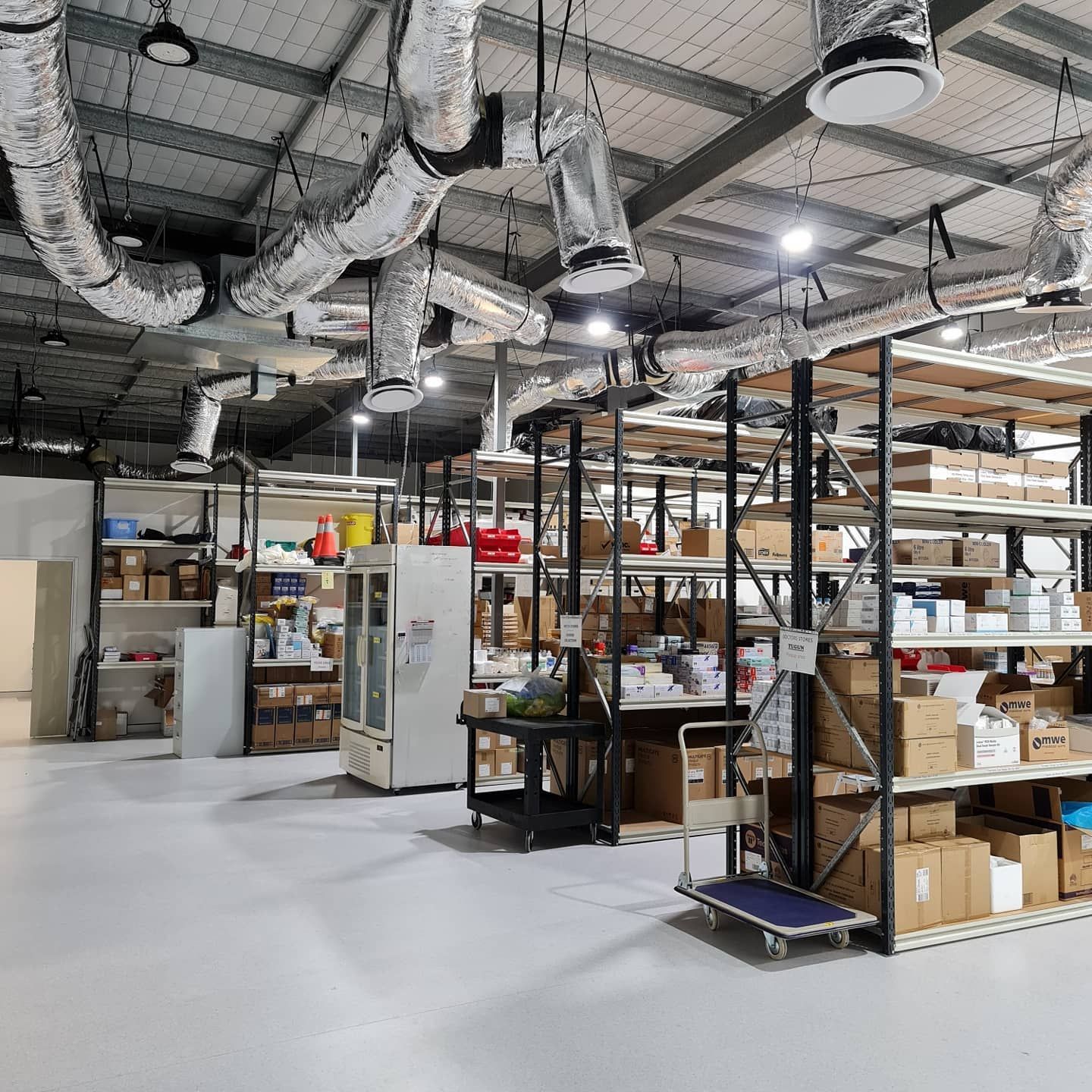 Warehouse storage area with metal shelving, boxes, and exposed ductwork overhead