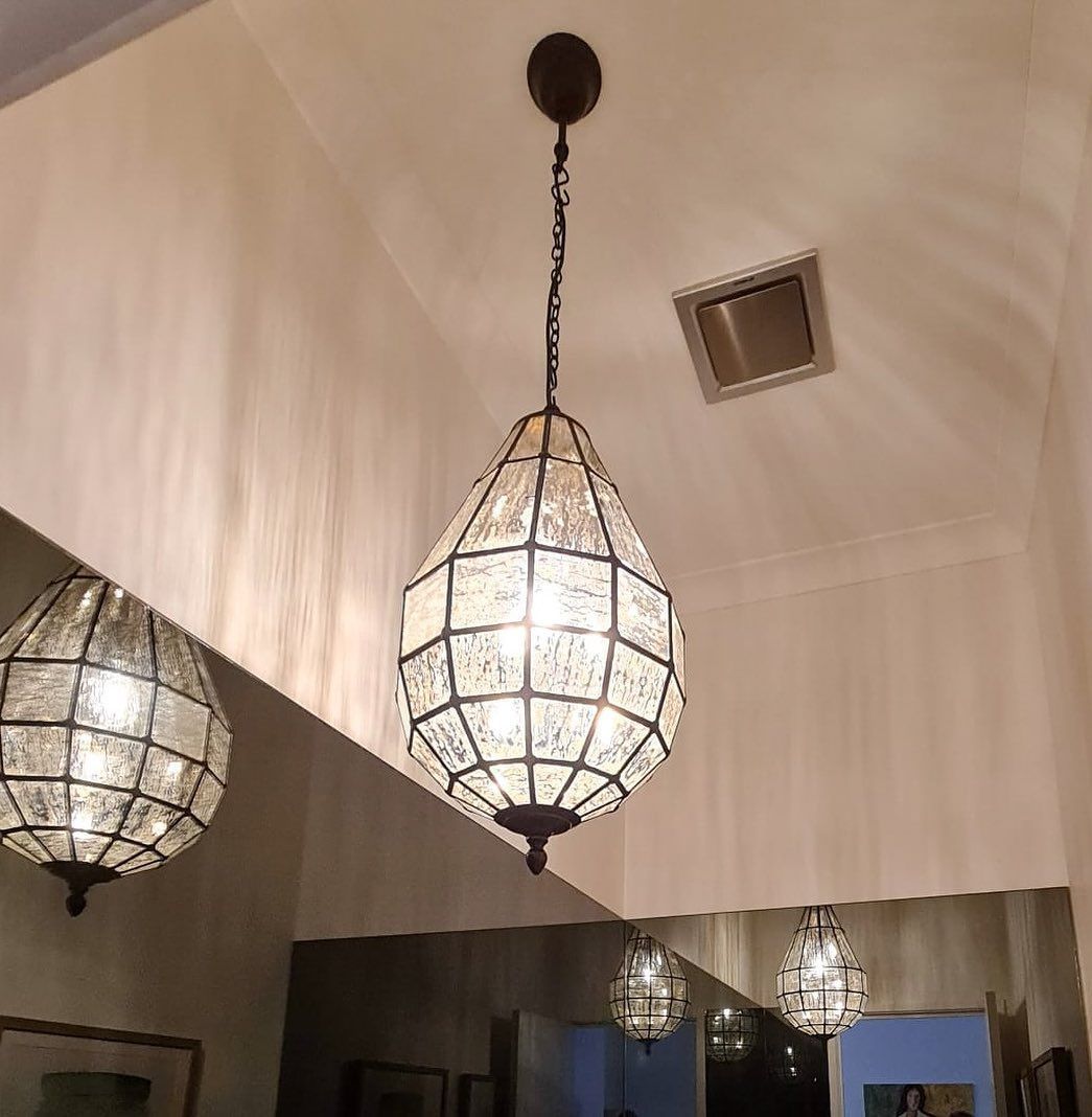 Decorative hanging lanterns with frosted glass glow in a high, vaulted indoor ceiling.