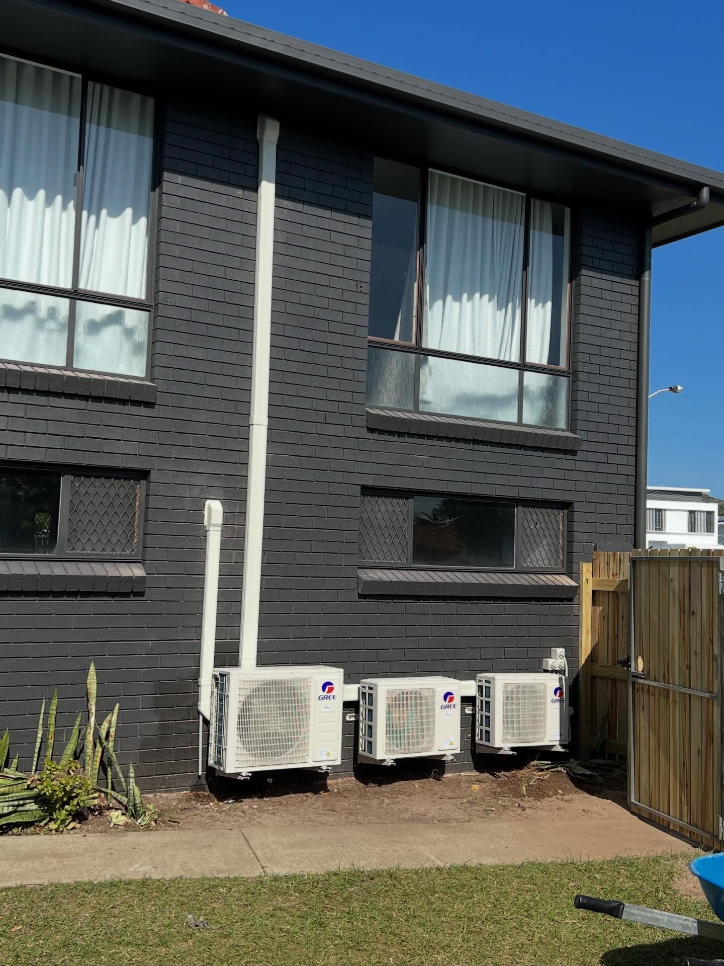 Black townhouse exterior with three outdoor AC units and a fenced yard.