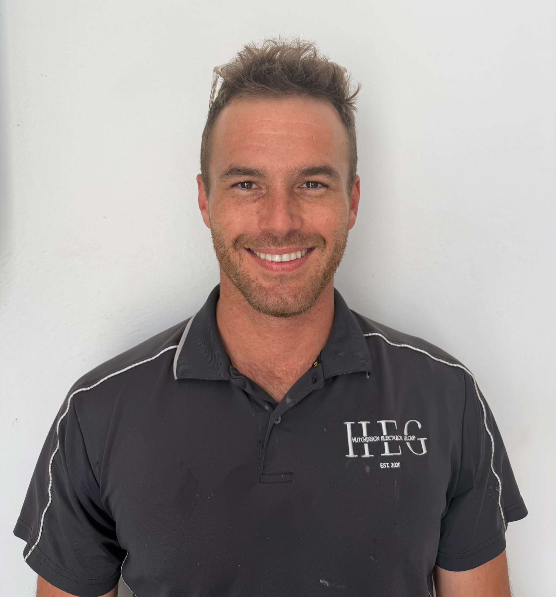 Smiling man in a dark gray polo shirt against a plain light background