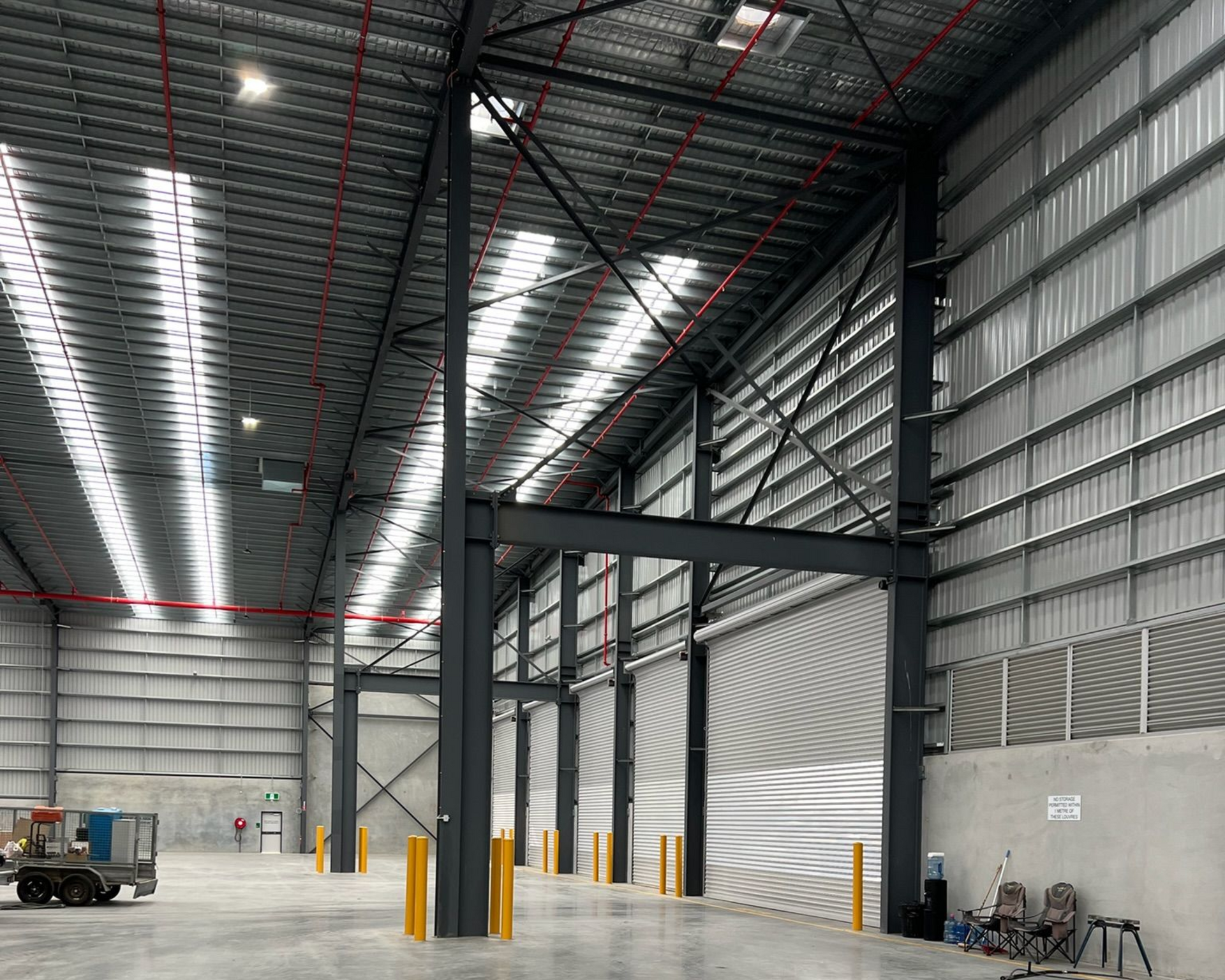 Empty industrial warehouse interior with metal beams, high ceiling, and concrete floor