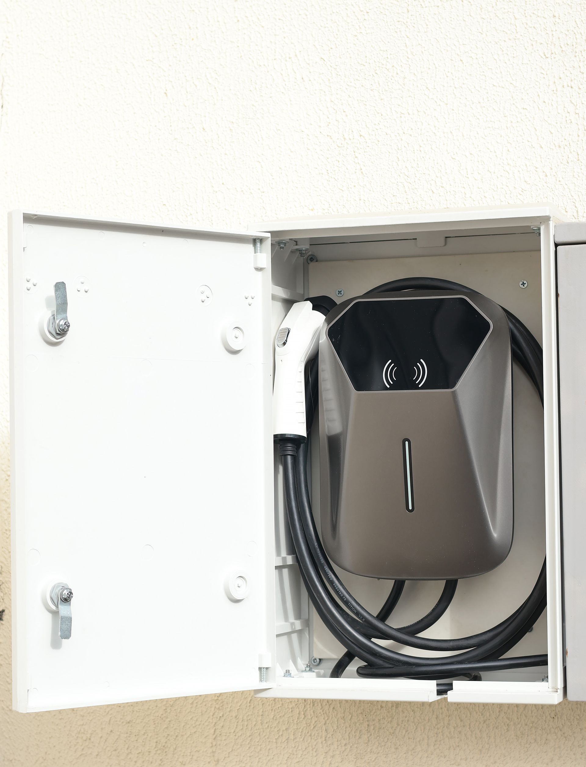 Open electrical cabinet with coiled cables and a mounted device inside