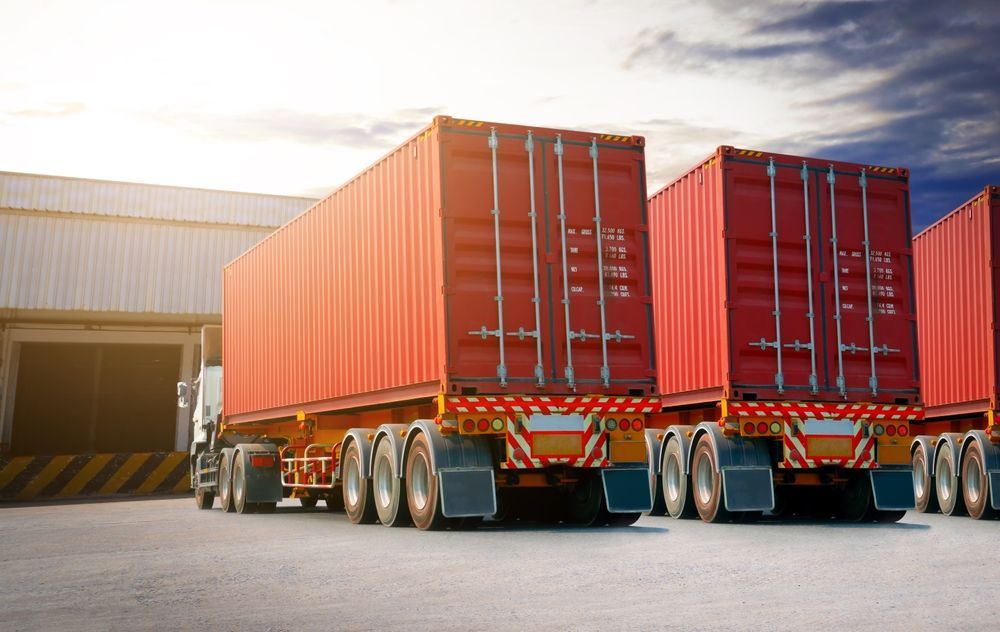 A Row Of Red Shipping Containers Are Parked In Front Of A Warehouse — ABC Driving School Central Coast In Umina Beach, NSW