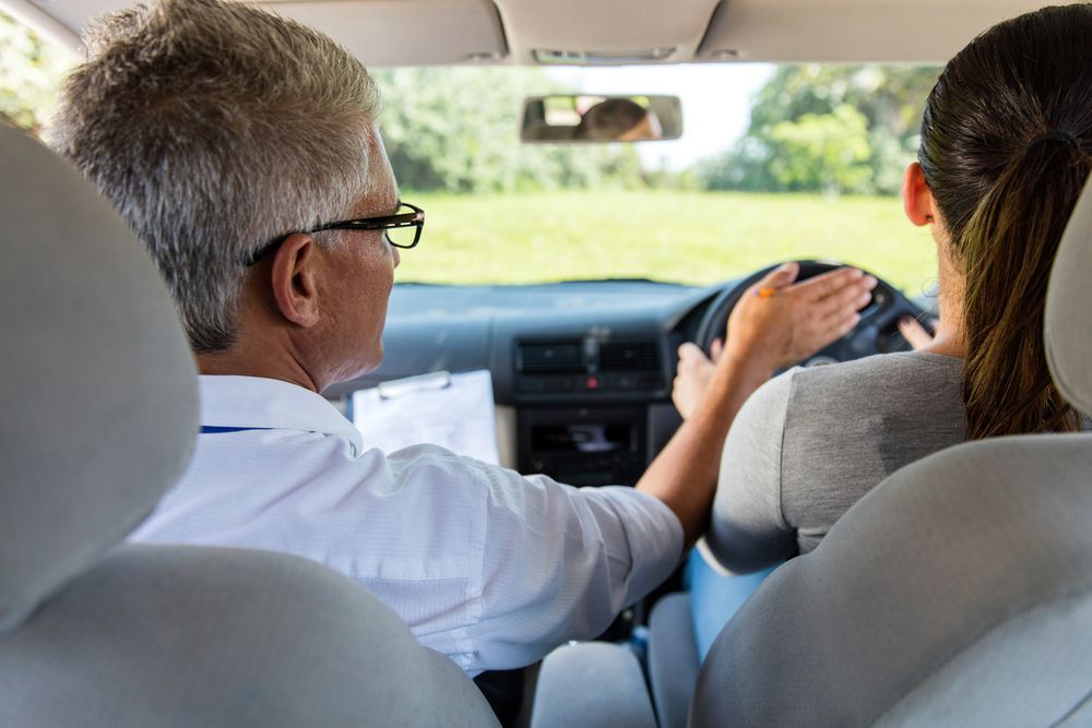 A Man Is Teaching A Woman How To Drive A Car — ABC Driving School Central Coast In Umina Beach, NSW