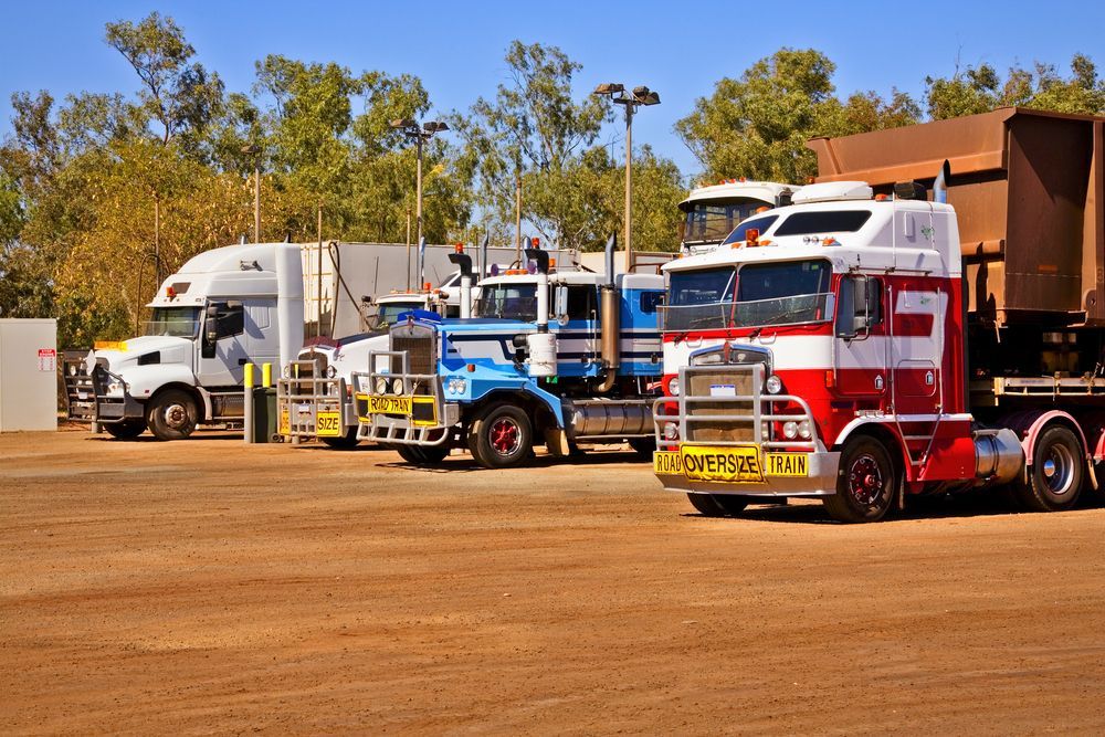 A Row Of Semi Trucks Are Parked In A Dirt Lot — ABC Driving School Central Coast In Umina Beach, NSW