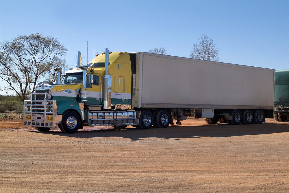 A Yellow And Green Semi Truck Is Parked On A Dirt Road — ABC Driving School Central Coast In Umina Beach, NSW
