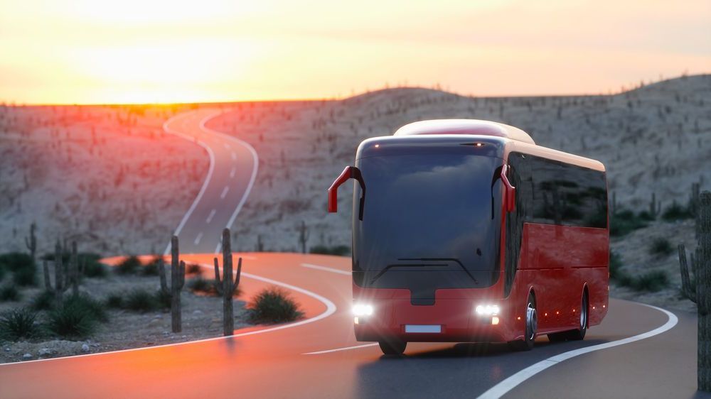A Red Bus Is Driving On The Highway With The Sun Setting — ABC Driving School Central Coast In Umina Beach, NSW