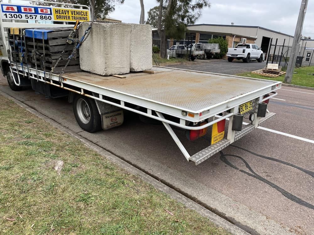 A Flatbed Truck Is Parked On The Side Of The Road — ABC Driving School Central Coast In Umina Beach, NSW