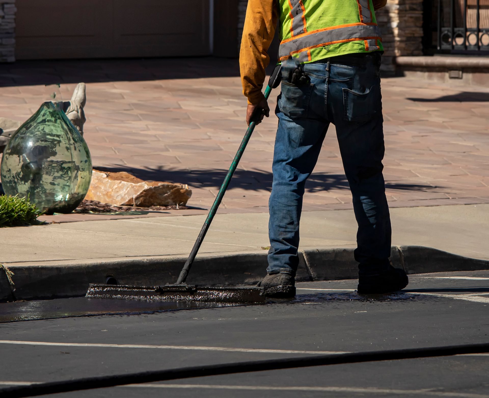 worker providing sealcoating services in Perrysburg, OH during asphalt resurfacing project.
