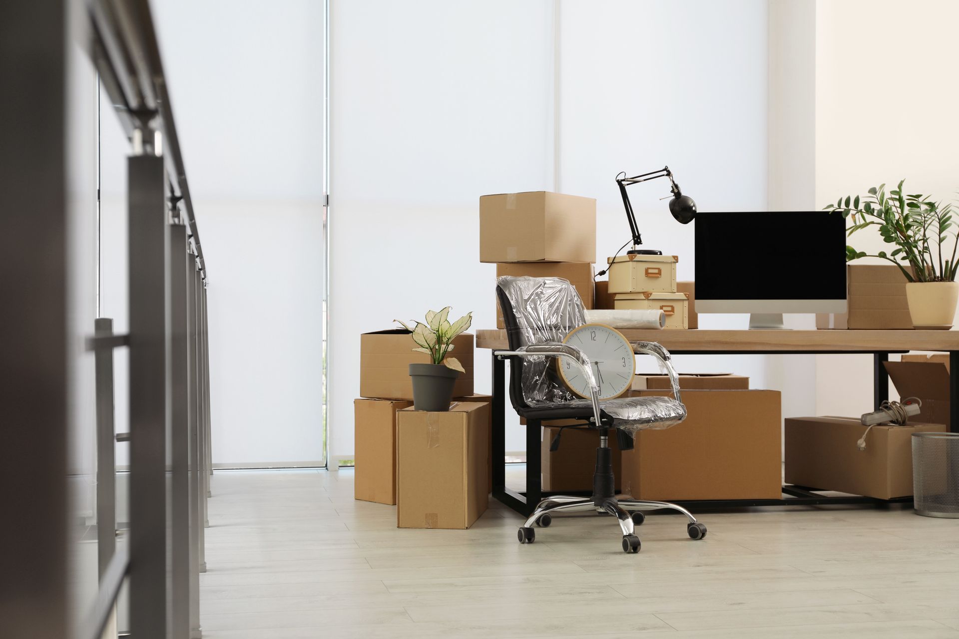 un ufficio con scrivania, sedia, computer e scatole sul pavimento.