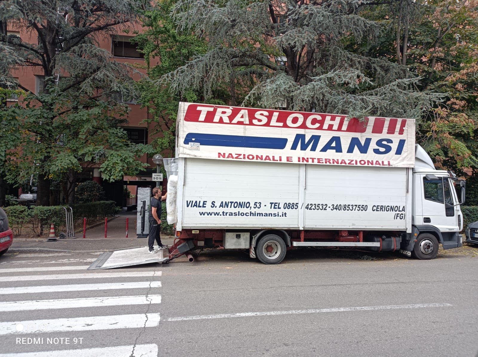 sul ciglio della strada è parcheggiato un camion bianco con la scritta mansi sulla fiancata.