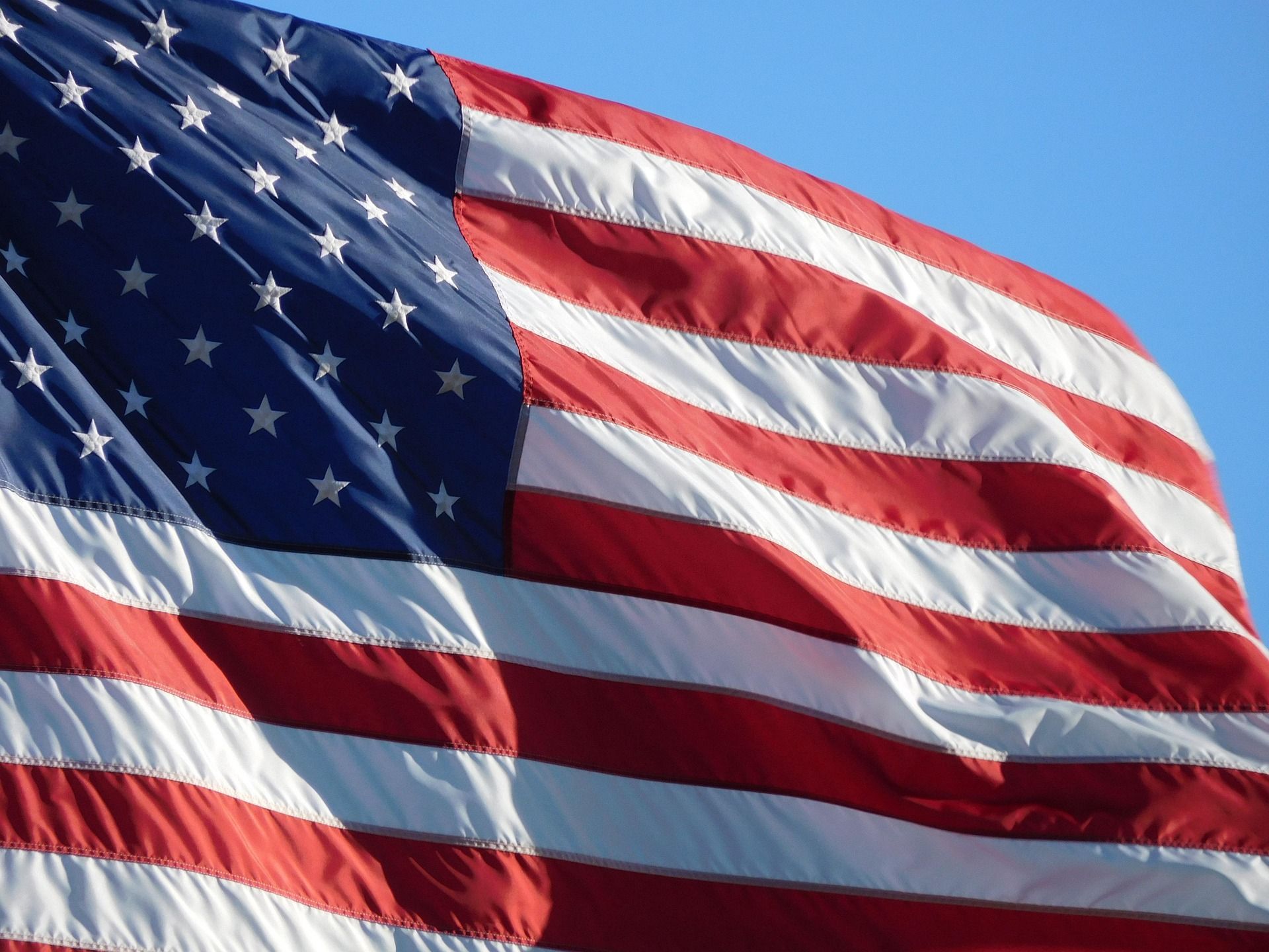An american flag is flying in the wind against a blue sky