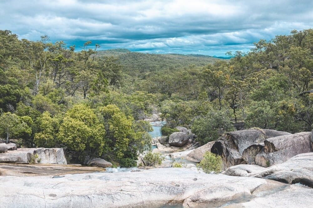 A River Runs Through A Lush Green Forest Surrounded By Rocks And Trees — The Portaloo Co in Mareeba, QLD