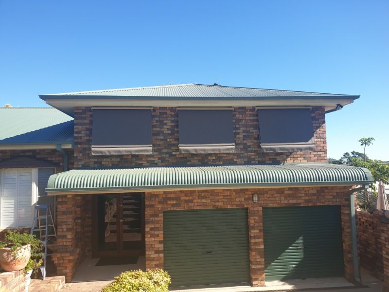 A Large Brick House With a Green Garage Door — BTS Blinds & Awnings in Wee Waa, NSW