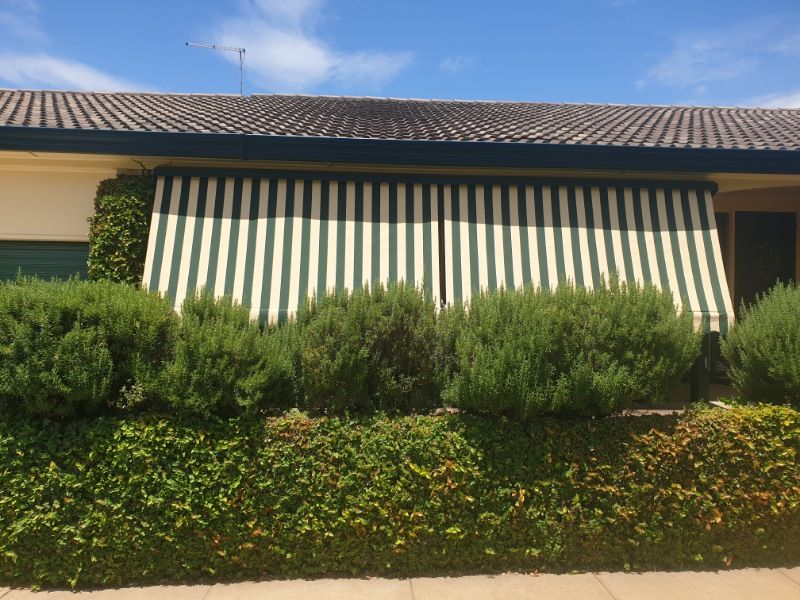 A House With a Striped Awning on the Front of It — BTS Blinds & Awnings in Scone, NSW
