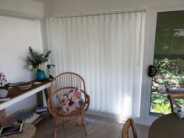A Living Room With a Chair , Table , and Window With White Blinds — BTS Blinds & Awnings in Gunnedah, NSW
