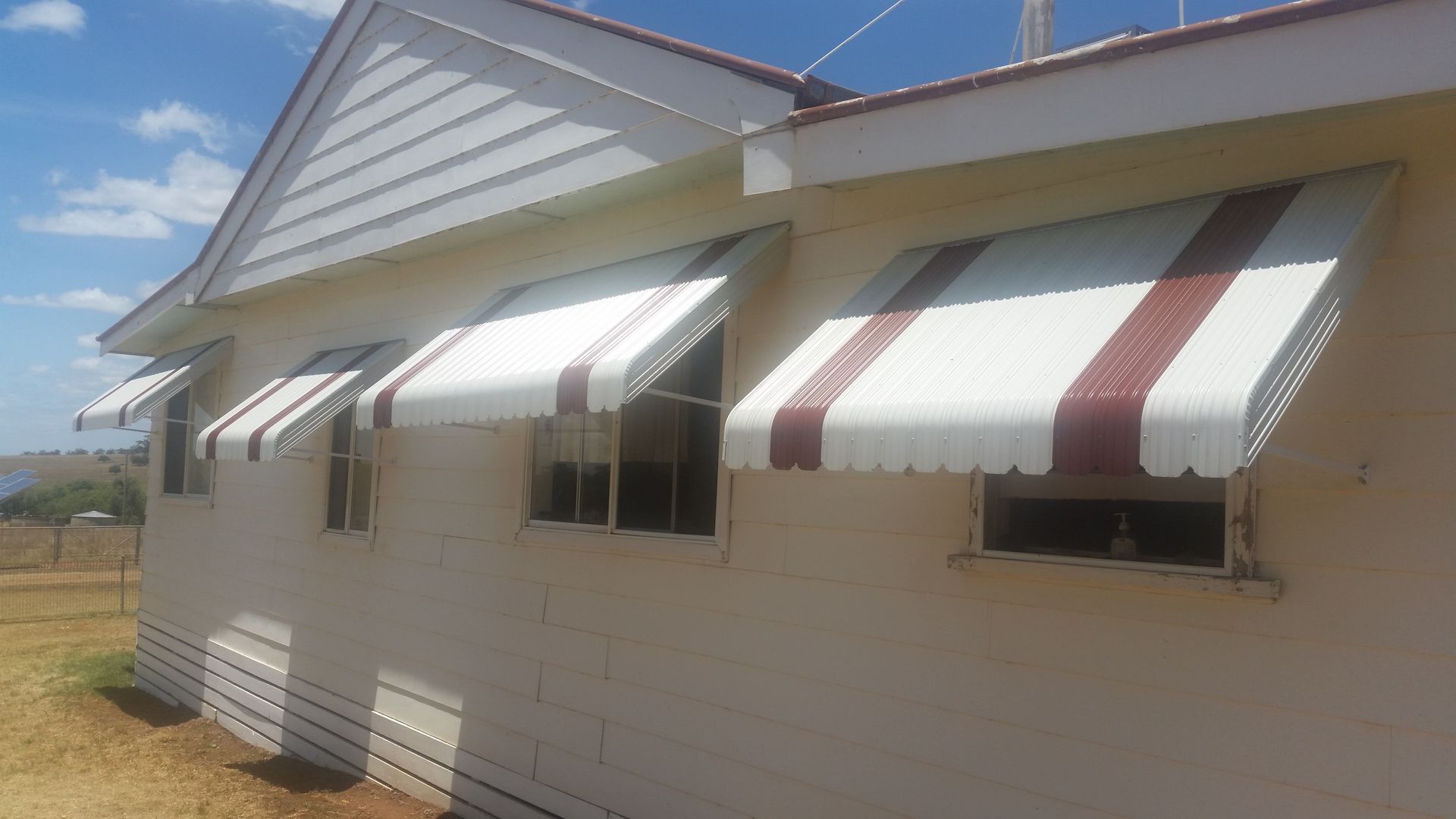A White House With Red and White Awnings on the Windows — BTS Blinds & Awnings in Gunnedah, NSW