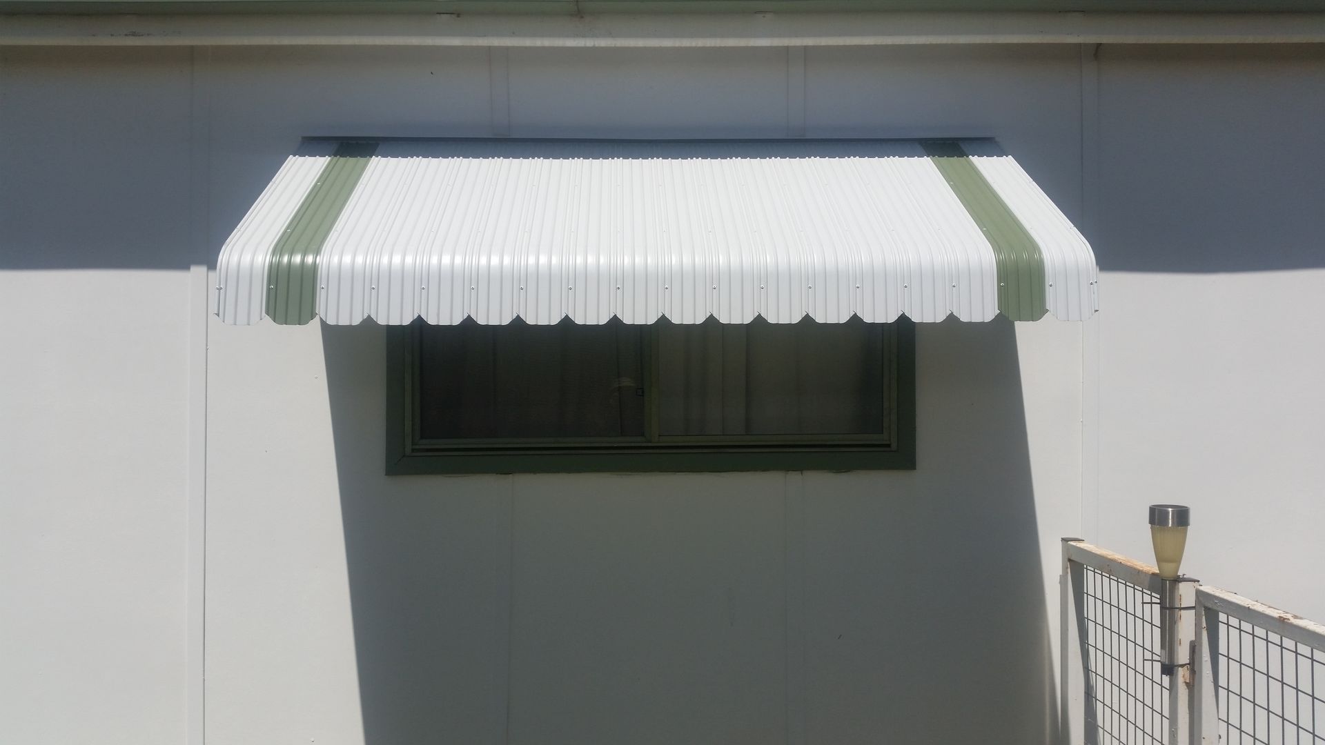 A White Awning is Hanging Over a Window on the Side of a House — BTS Blinds & Awnings in Gunnedah, NSW